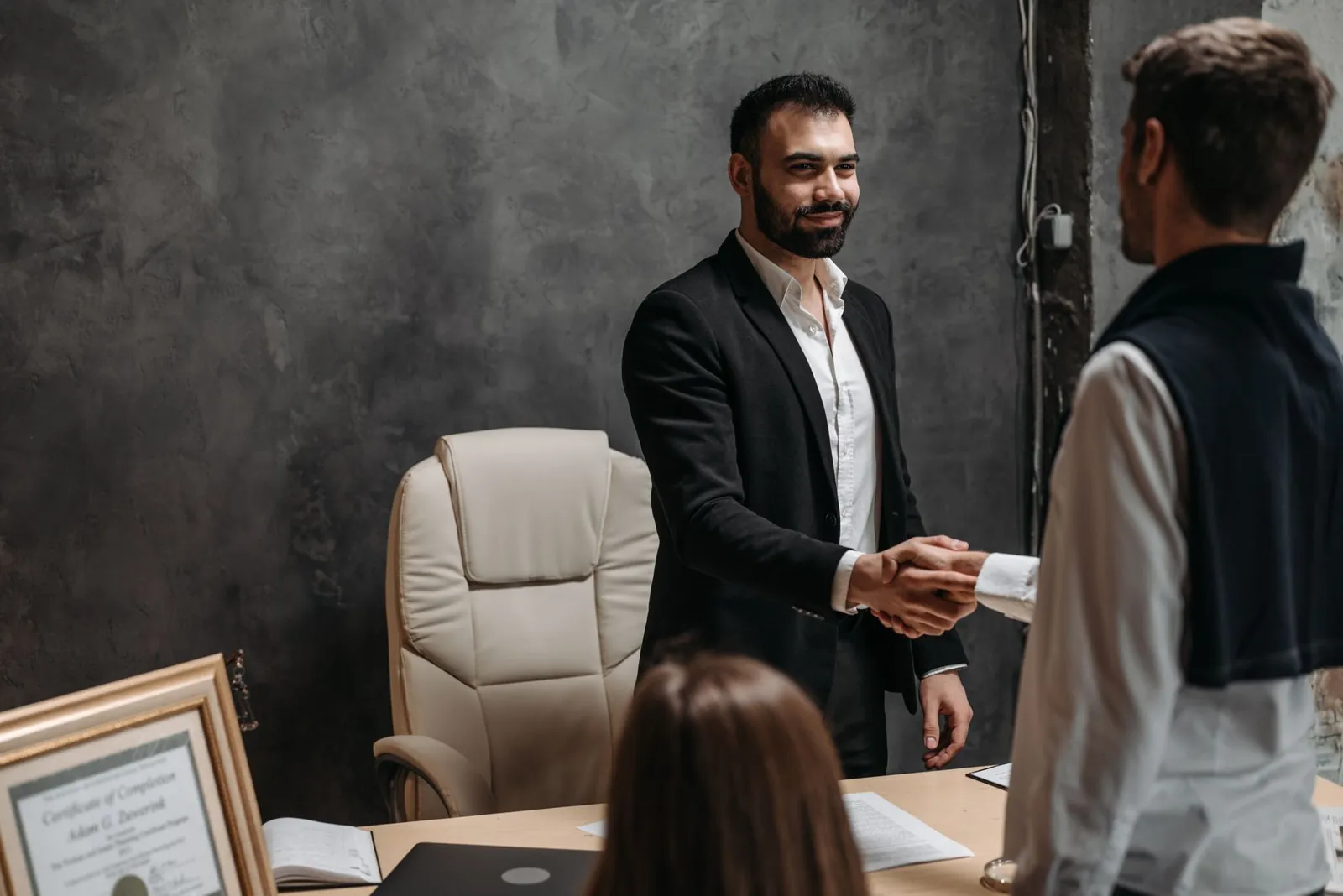 Advisor greeting a client with a handshake in a professional office